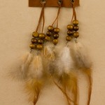 Feathers attached through grommets onto a strip of leather