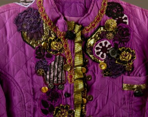 Detail of button, bead, and ribbon embellishment at top of magenta jacket